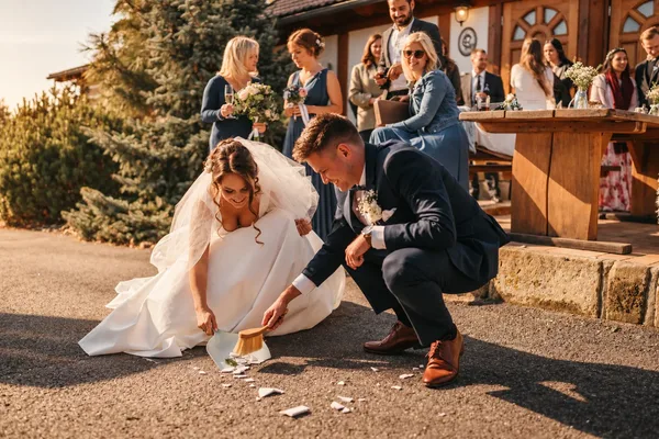 Novomanželé zametají rozbitý talíř